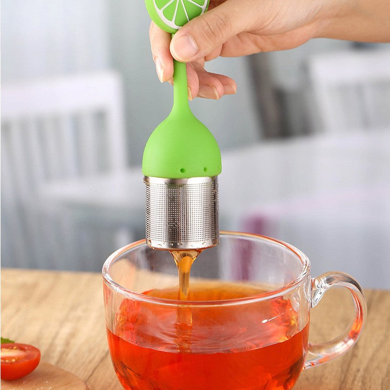 Main retirant un Infuseur à Thé | Couleurs d'Été style citron vert d'une infusion ambrée de sa tasse en verre