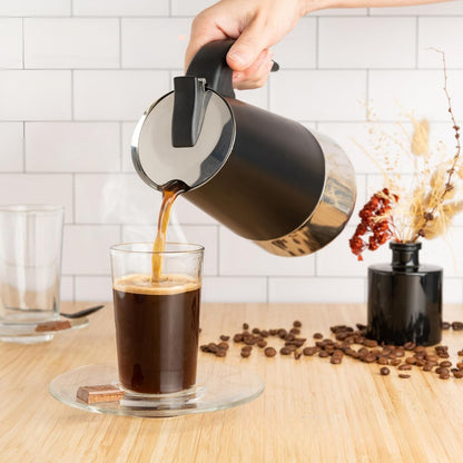 Cafetière italienne induction Karisme versant café fumant dans verre transparent avec belle couche de mousse