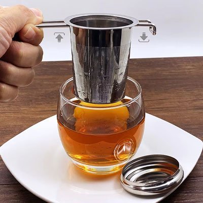 Infuseur à thé en inox 304 poignées doubles au-dessus d'un verre à thé transparent avec son repose-filtre