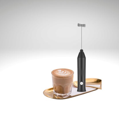 Mousseur lait noir Le Vortex posé sur plateau doré à côté d'une tasse de café latté.