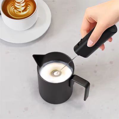 Préparation d'une mousse légère directement dans un pichet noir avec le mousseur a lait | Crémeux Express pour un café latte artistique.