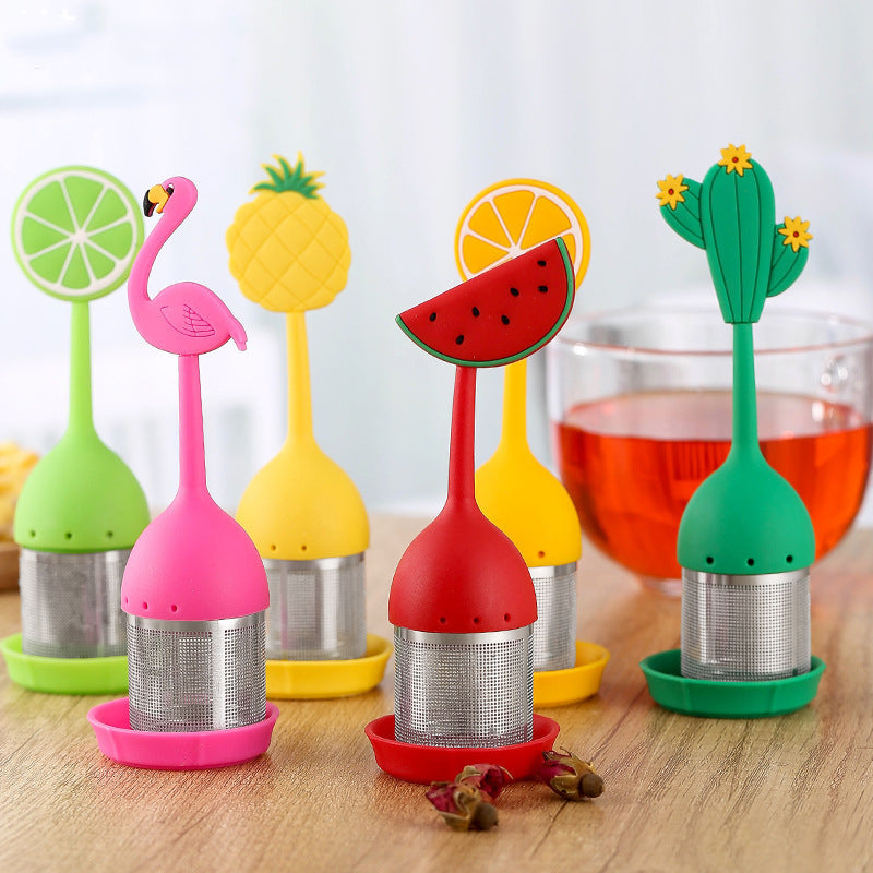 Présentation de toutes les variantes de l' Infuseur à Thé | Couleurs d'Été en inox avec sa coupelle de récupération avec en arrière plan  une tasse de thé en infusion
