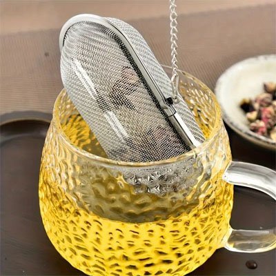 Zoom sur Boule à Thé | Inox Perfect avec chaînette infusant des feuilles dans une tasse en verre à relief martelé